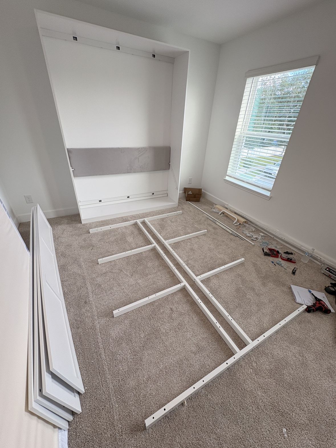 Murphy bed frame parts laid out on the floor mid-assembly